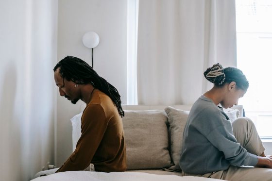 Couple assis dos a dos sur un lit apres une infidelite
